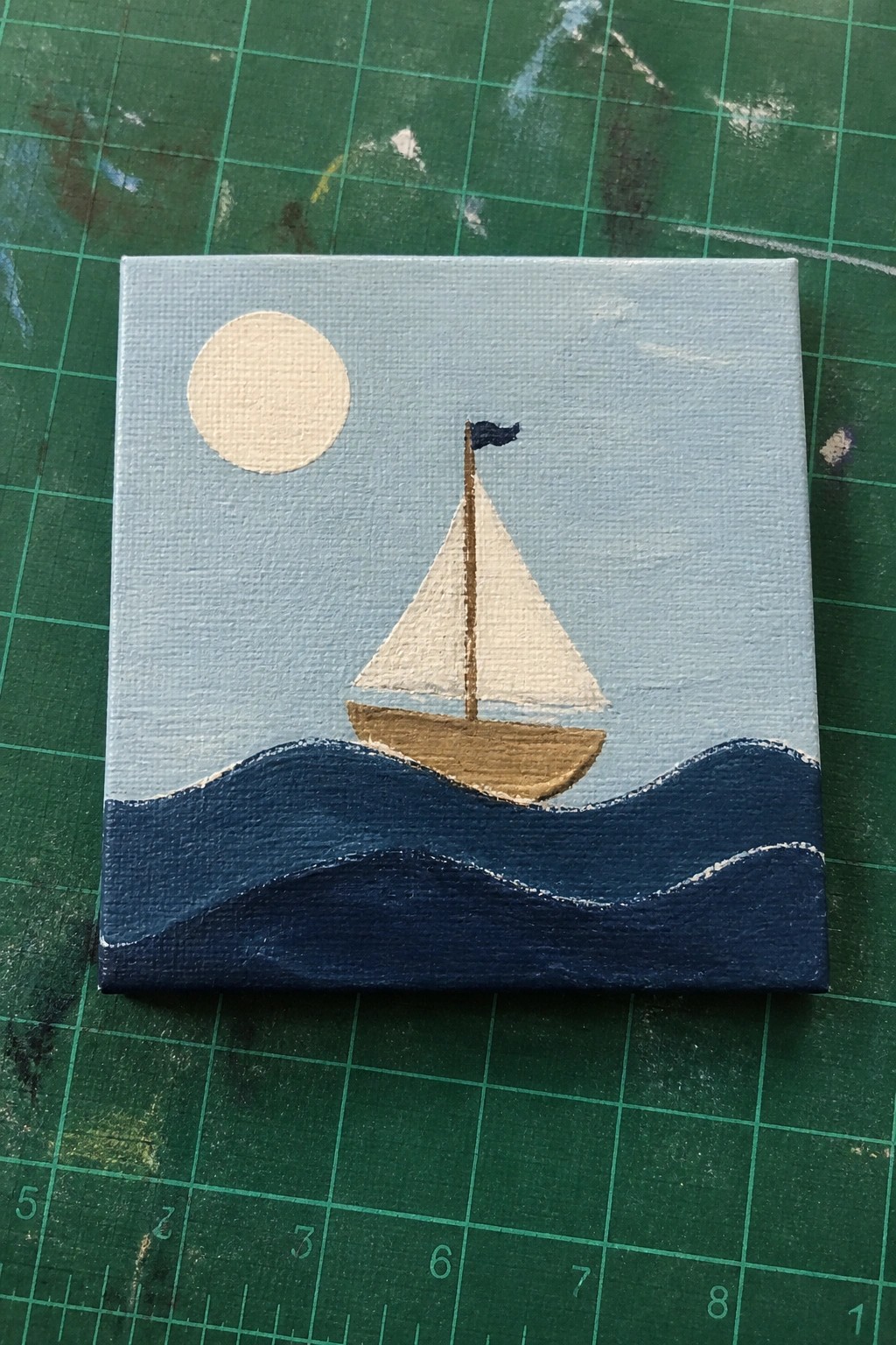 Miniature painting of white-sailed boat on wavy blue sea under pale sun