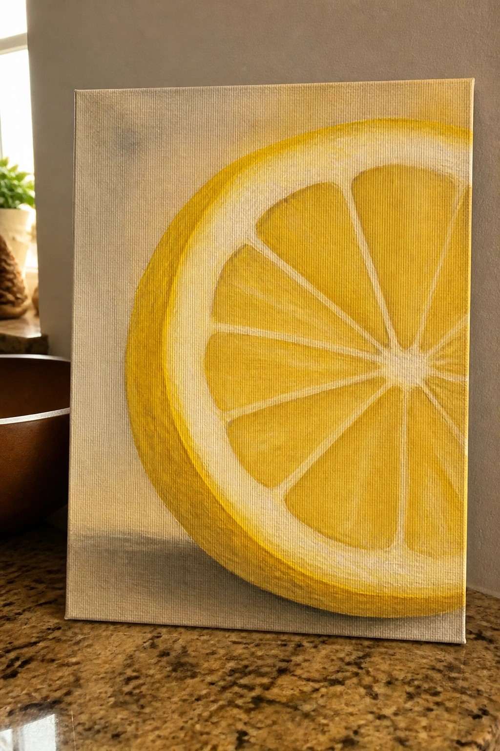 Yellow lemon slice painting on canvas propped on granite countertop