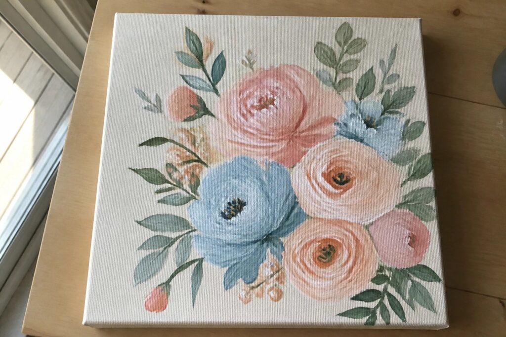 Floral canvas painting with pink, blue, peach, and white blooms and green leaves on wood