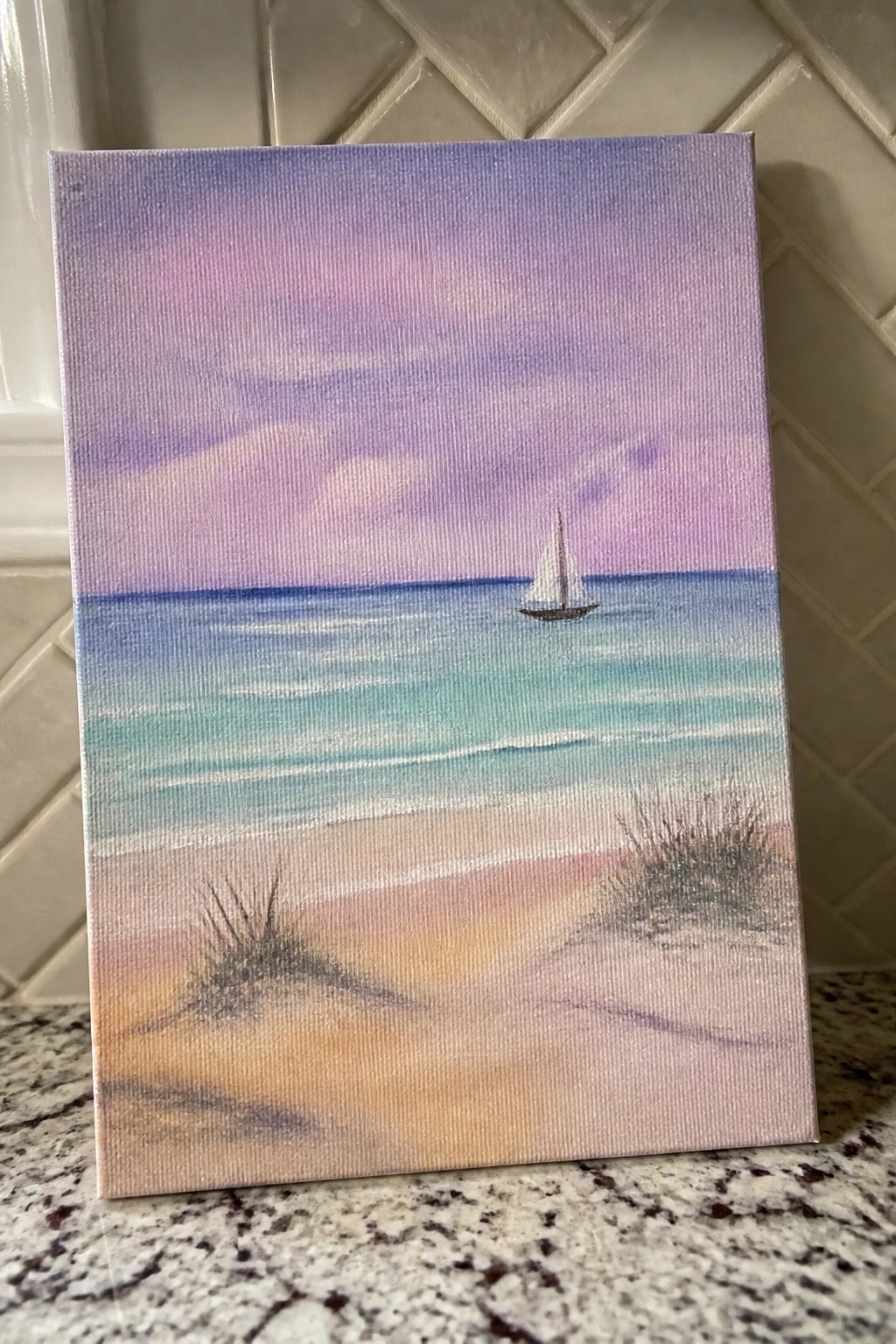 Canvas painting of sailboat on ocean under purple-pink sky with sandy beach foreground