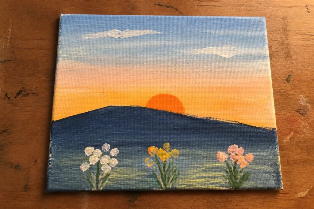 Sunset painting on canvas with orange sun, blue hills, and three wildflowers.
