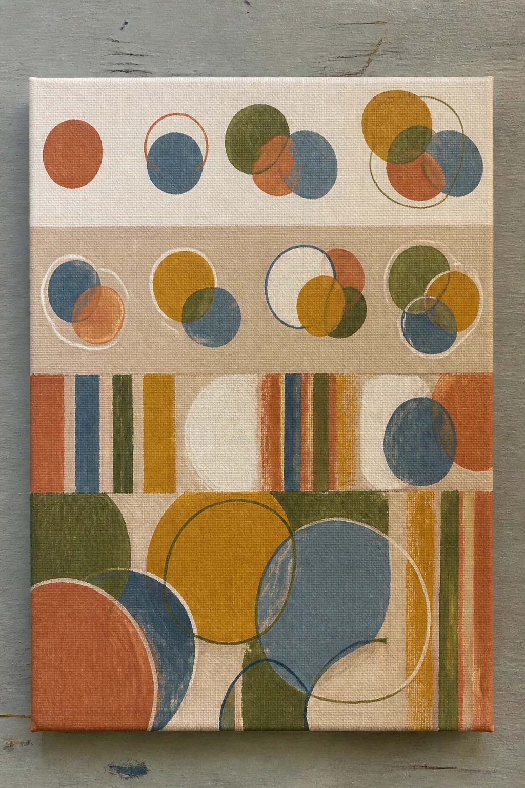 Abstract canvas painting with overlapping circles and colorful vertical stripes in earth tones.