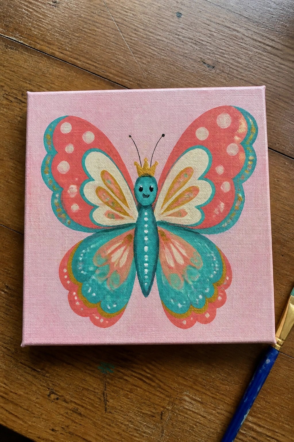 Colorful crowned butterfly with polka-dotted wings painted on pink canvas