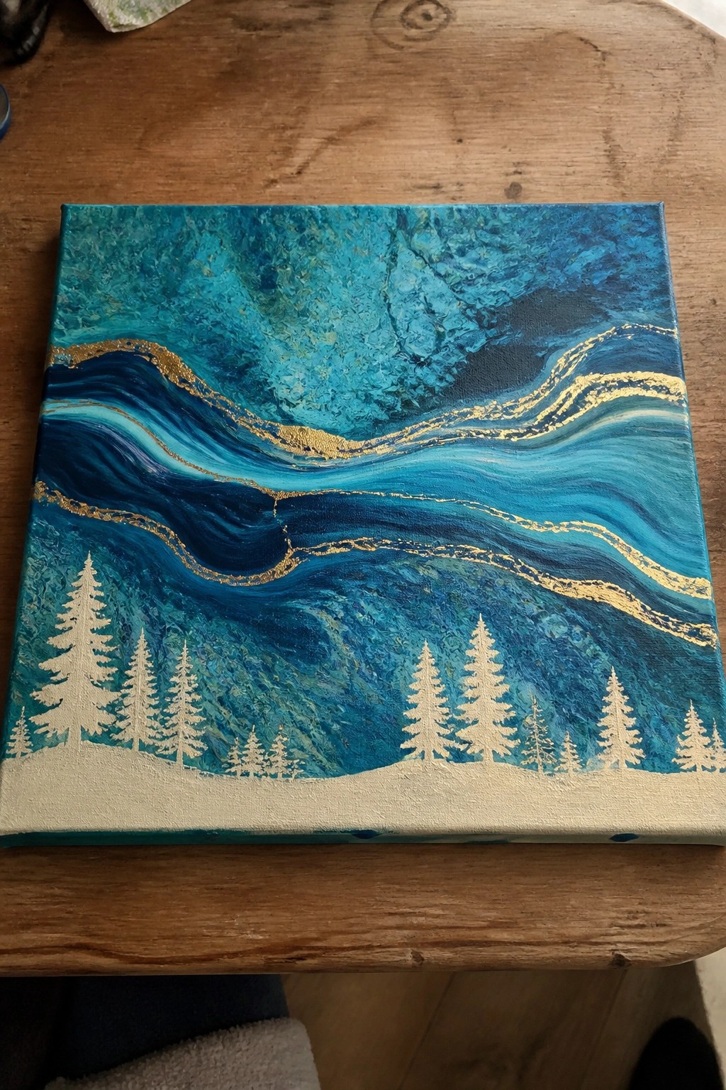 Swirling blue and teal abstract painting with gold waves and white pine trees.