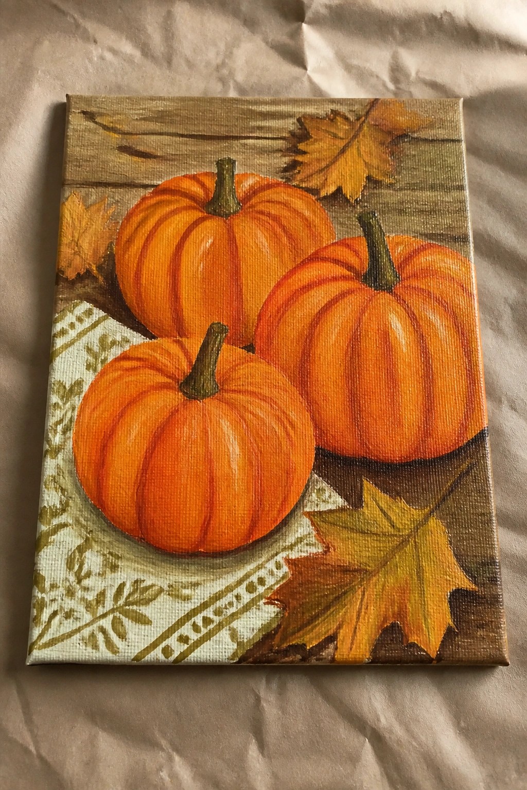 Three orange pumpkins with autumn leaves on rustic wood in a vibrant painting.