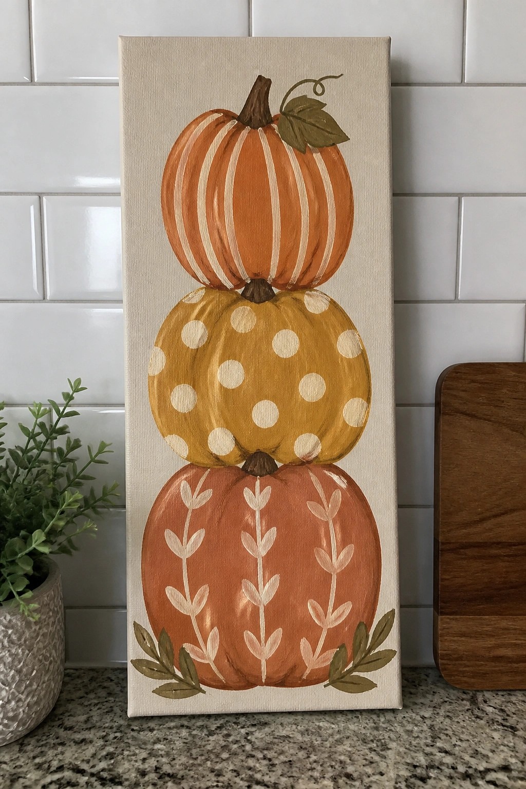 Canvas painting of three stacked decorative pumpkins with stripes, dots, and leaves
