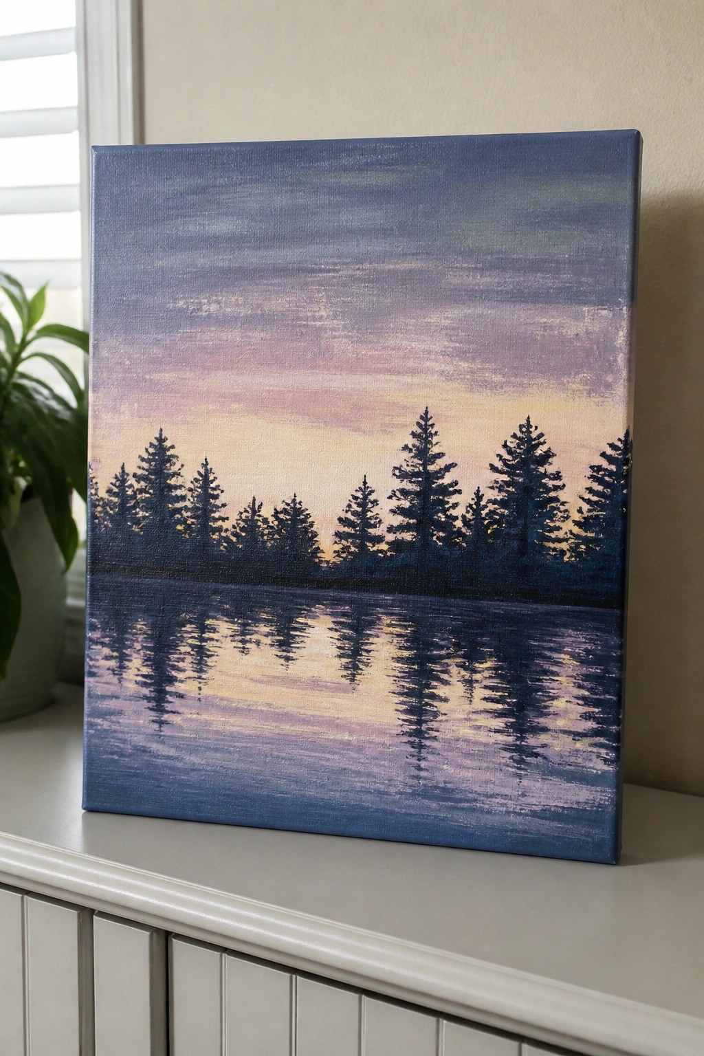 Canvas painting of pine trees reflected in lake under purple-pink sunset sky