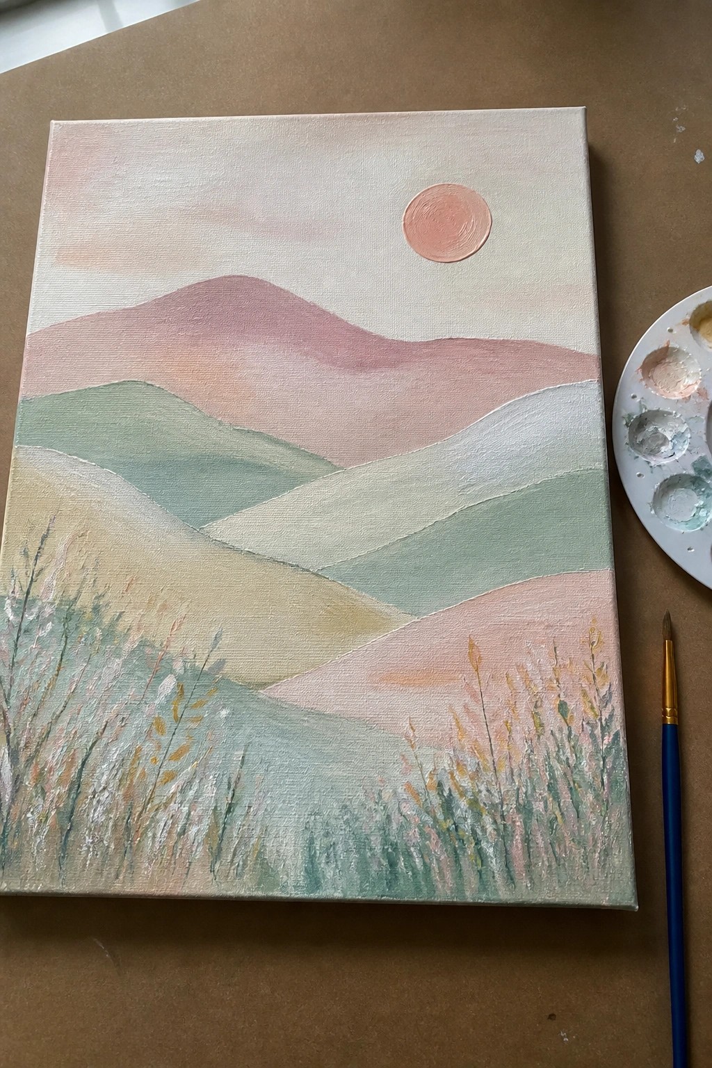 Pastel landscape painting on canvas with rolling hills, sun, flowers, palette, and brush