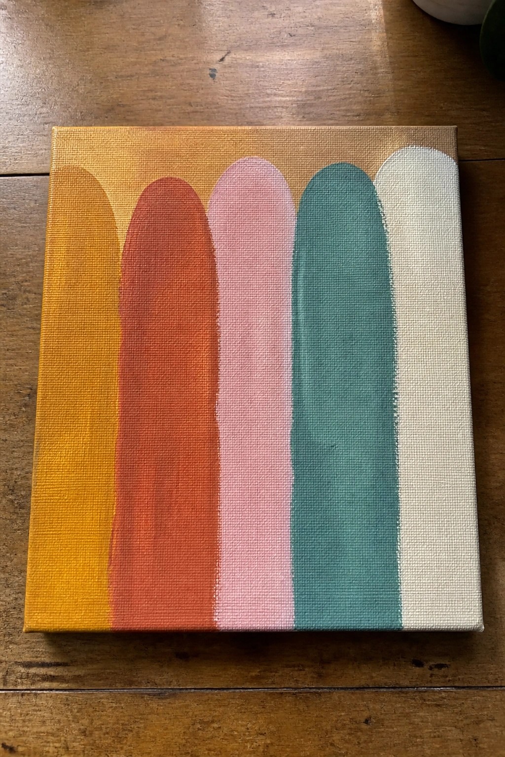 Abstract painting on canvas with vertical rounded arches in yellow, orange, red, pink, teal and white.