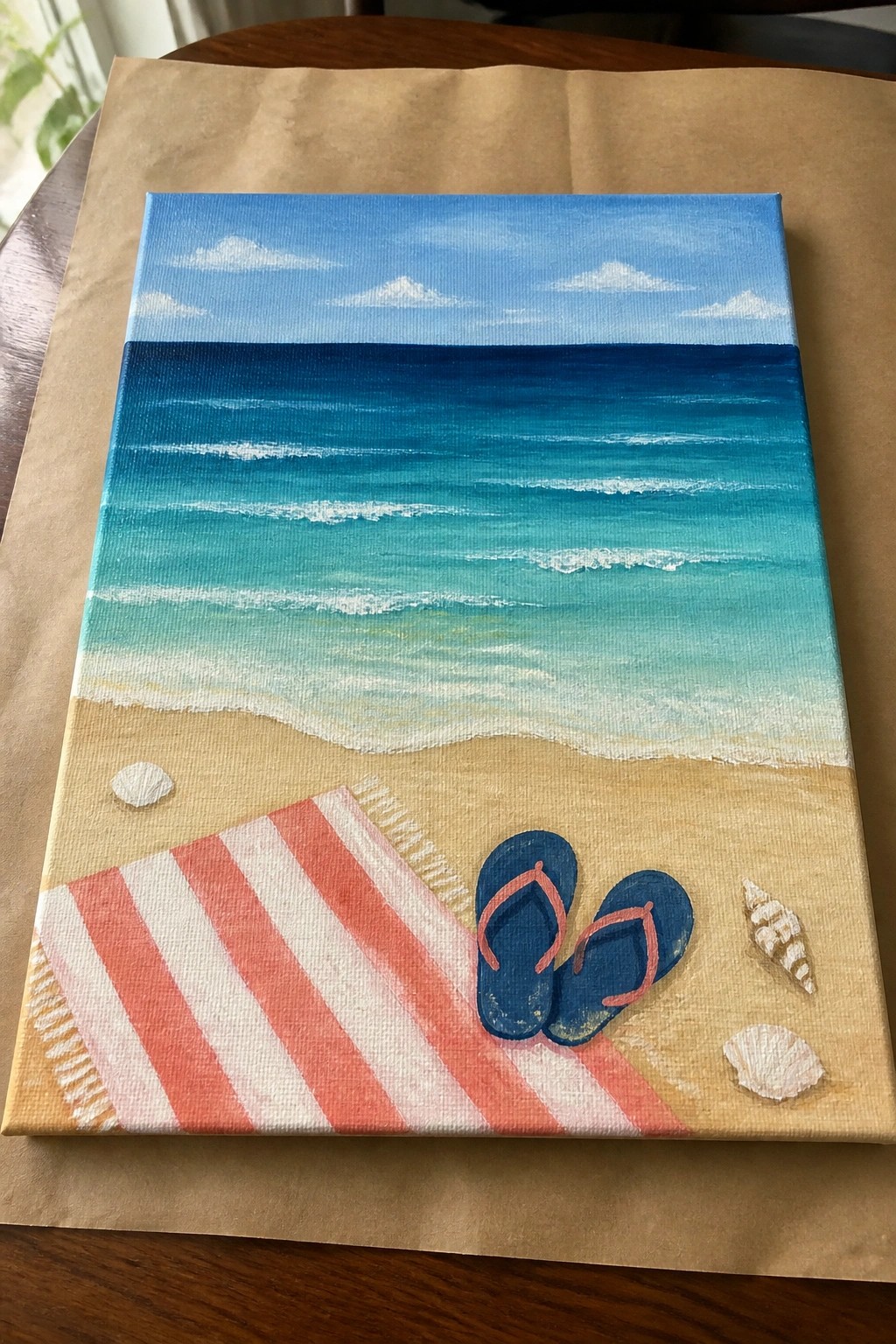 Acrylic beach painting with turquoise ocean, striped towel, blue flip-flops, and seashells on sand.