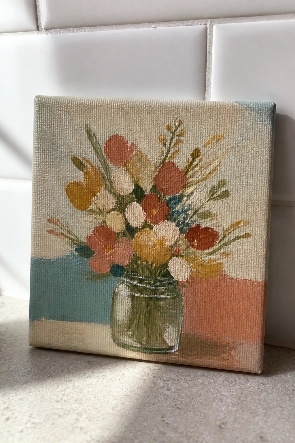 Small canvas painting of colorful flowers in a glass mason jar against tiles