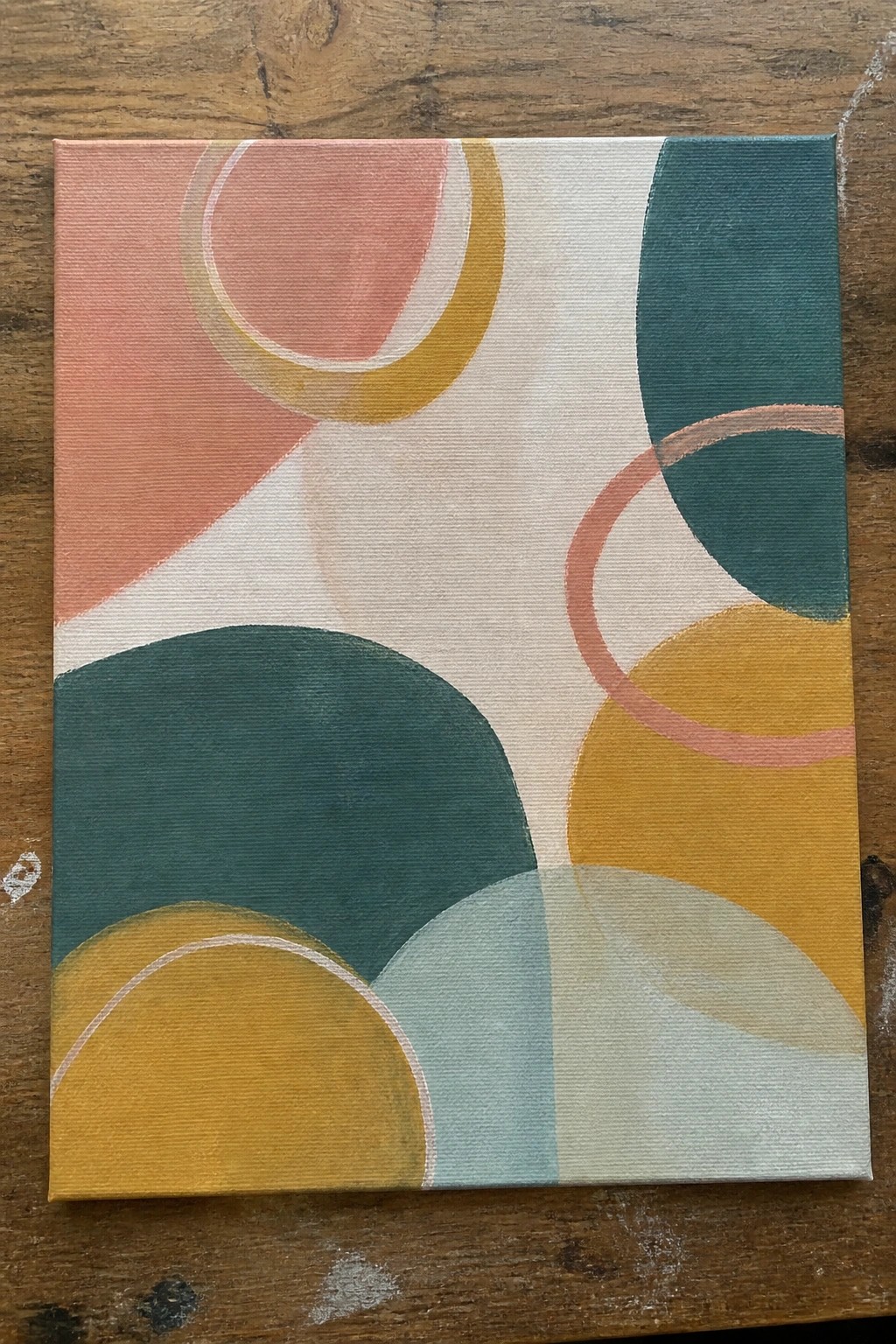 Abstract canvas painting with overlapping curves in coral, teal, yellow, and blue on wood.