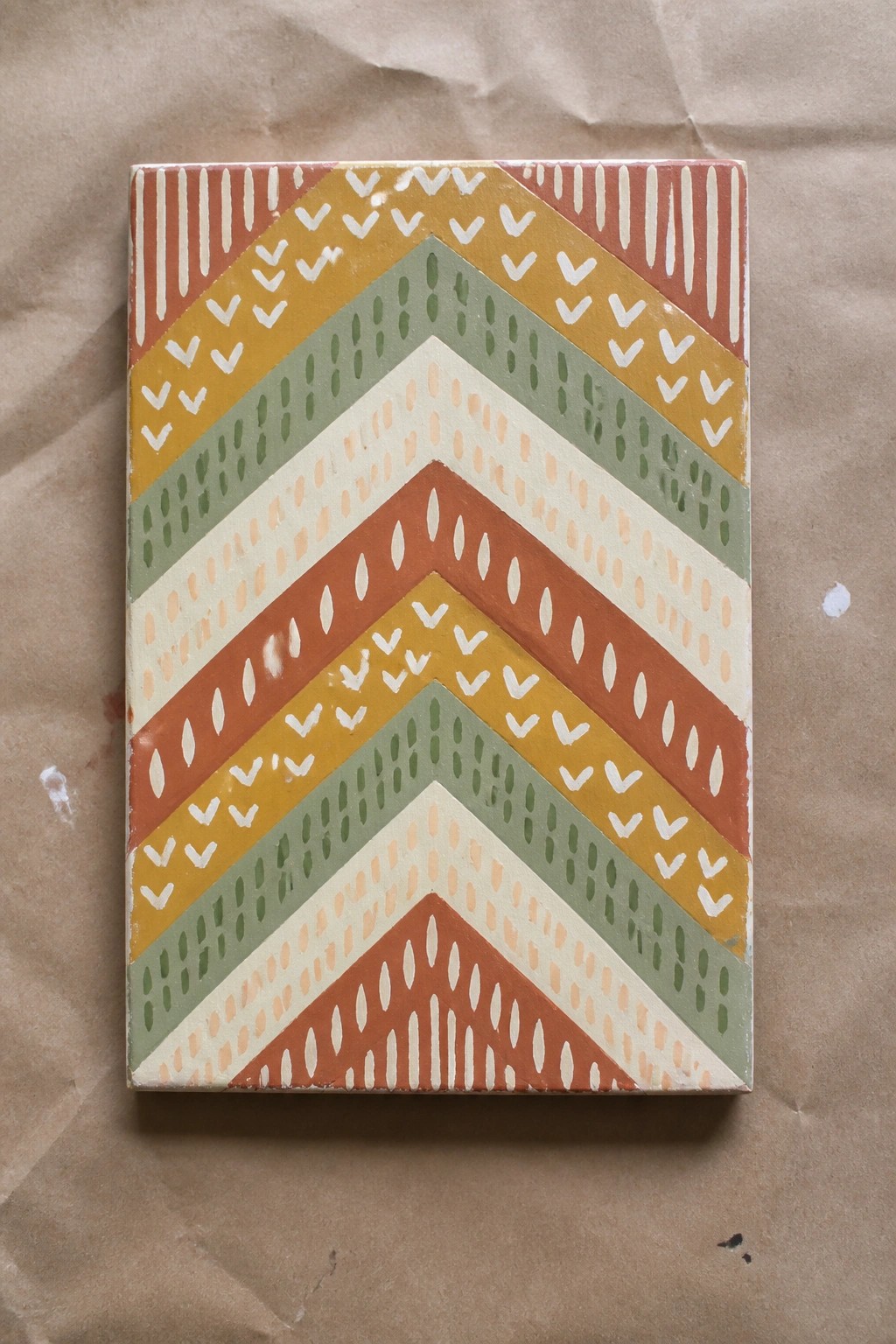 Colorful chevron-patterned tile with orange, yellow, green stripes and white motifs.