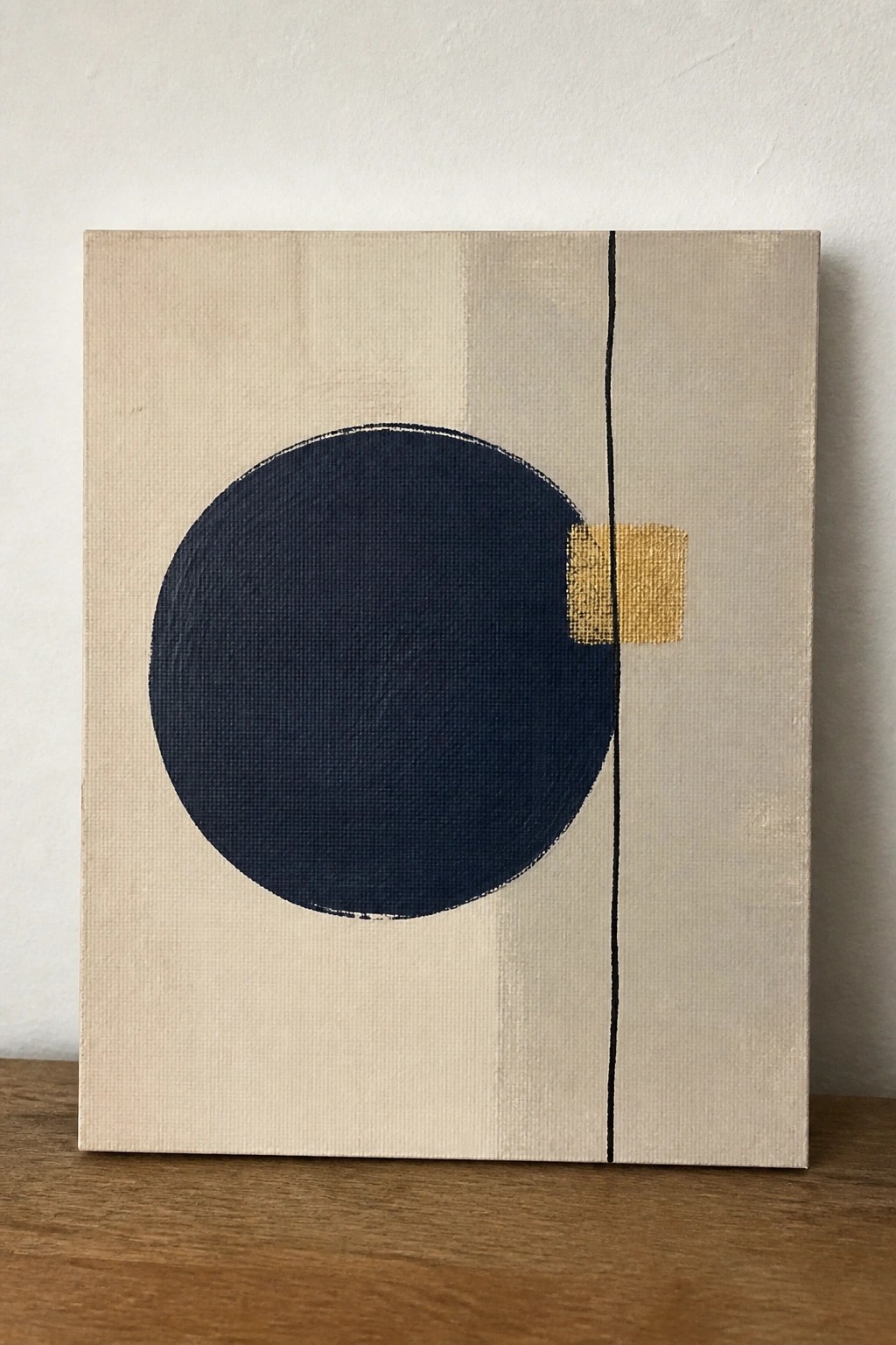Abstract canvas with large navy circle, gold square, and thin black line on beige.