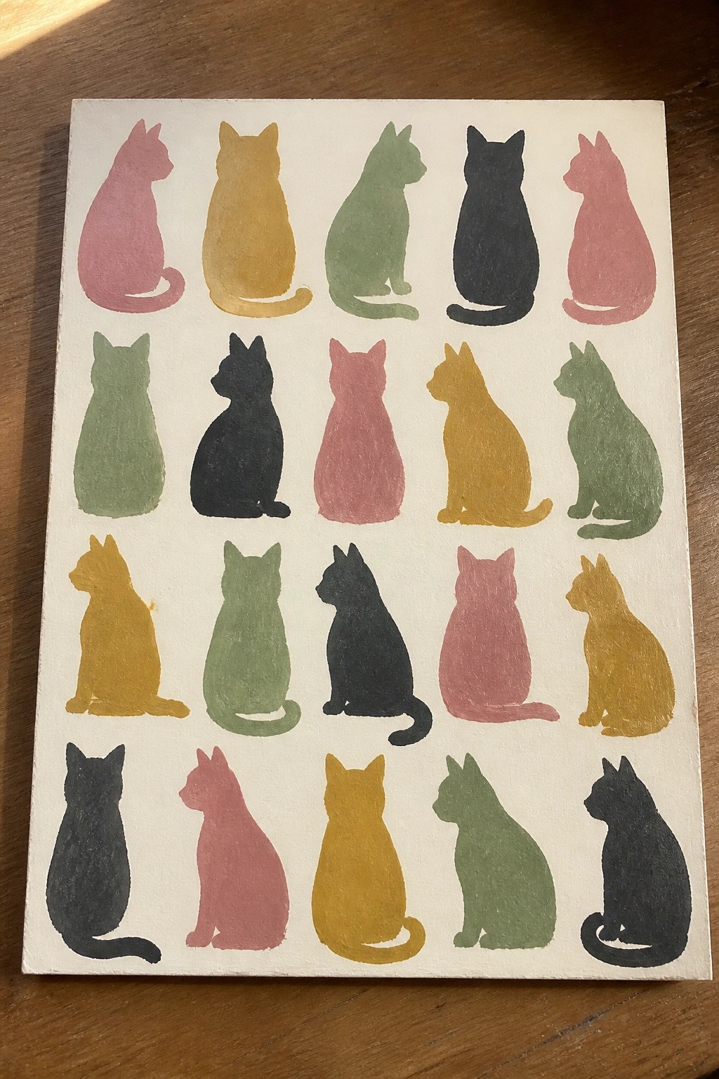 Colorful hand-painted cat silhouettes arranged in rows on white canvas.