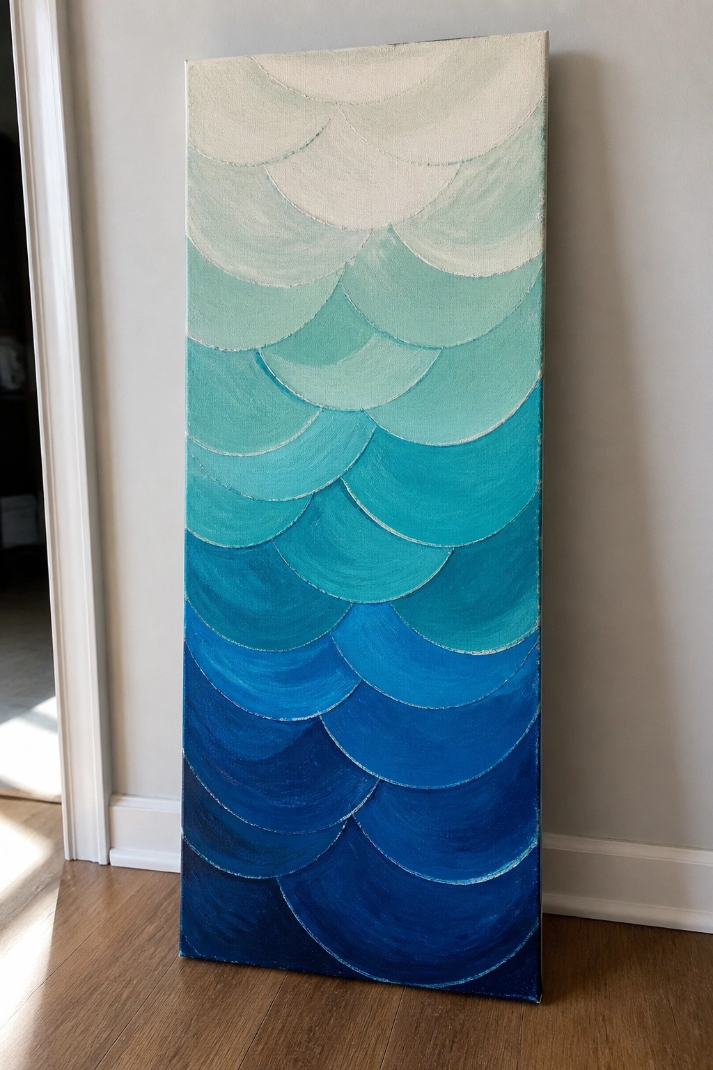 Tall abstract painting with overlapping blue-green scalloped scales leaning against wall