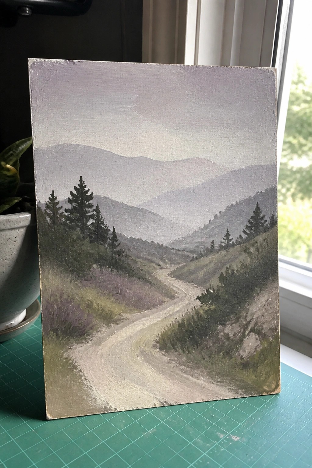 Painting of winding dirt path through misty hills with pine trees and mountains.