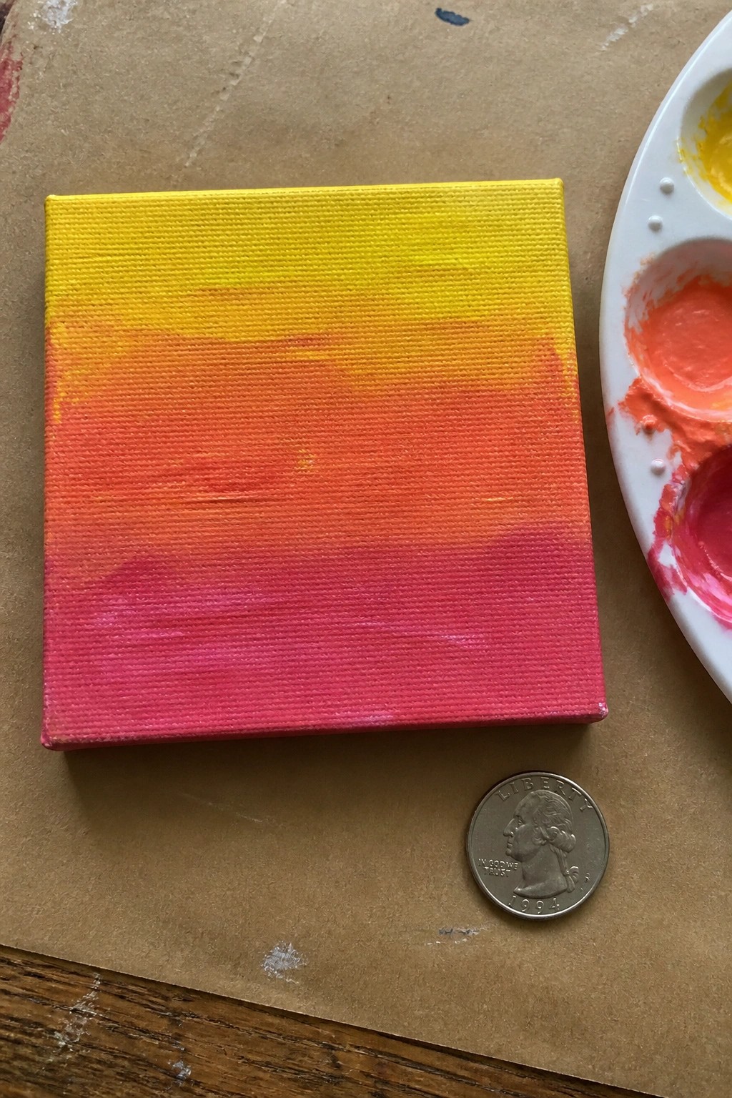 Small square canvas showing a smooth yellow to pink sunset gradient next to a quarter and paint palette.