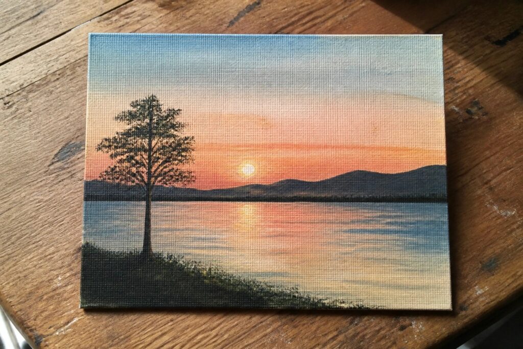 Canvas painting of silhouetted tree by lake at vibrant orange-pink sunset