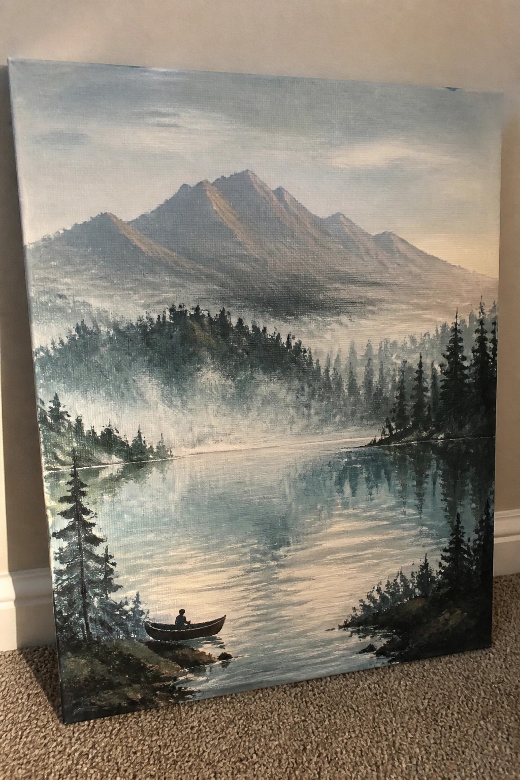 Misty mountain landscape painting with pine forests, fog, and a lone canoeist on calm water.