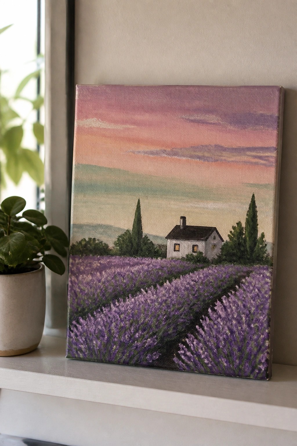 Landscape painting of purple lavender field, white house under pink-orange sunset sky beside plant.