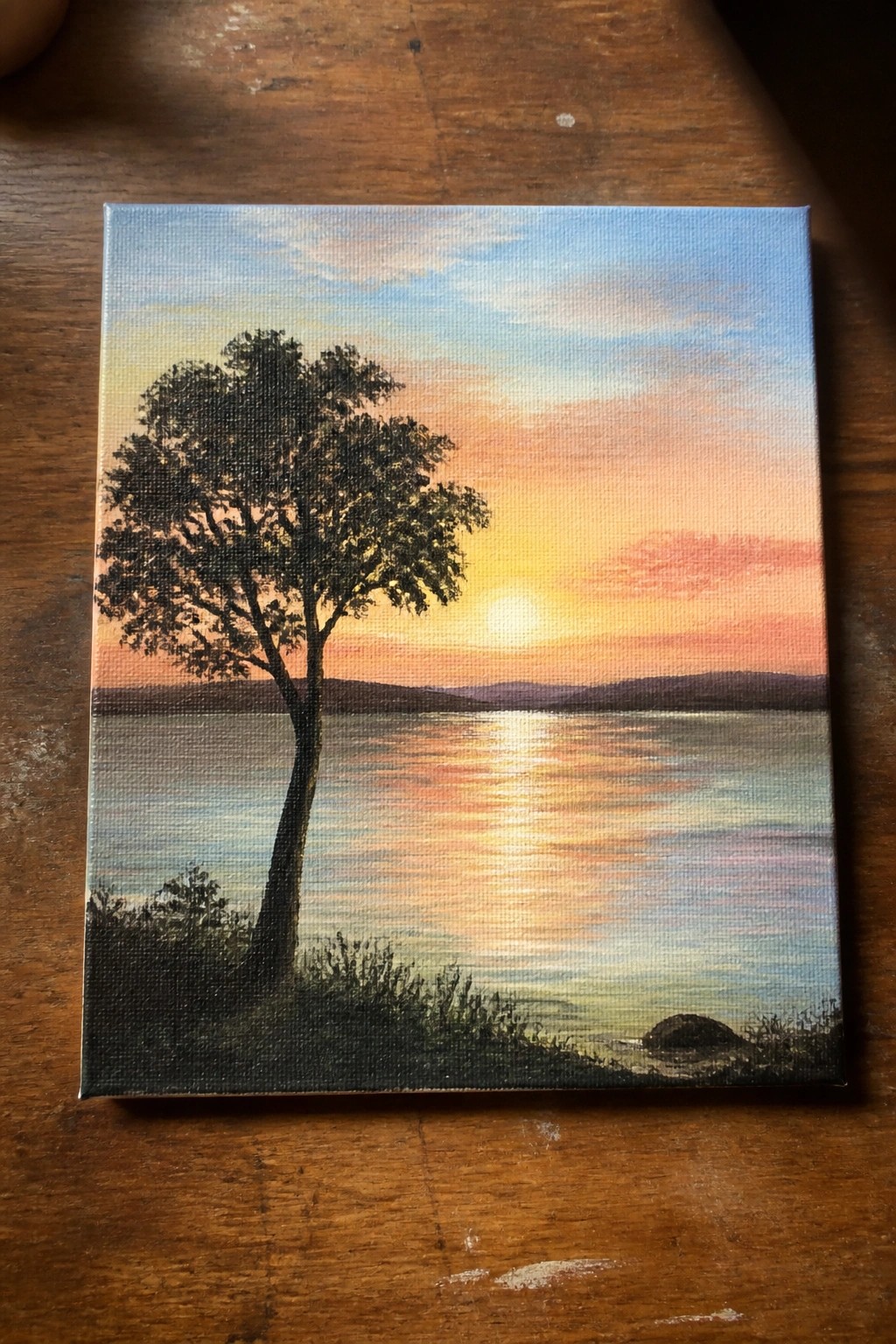 Canvas painting of silhouetted tree by lake at vibrant orange-pink sunset