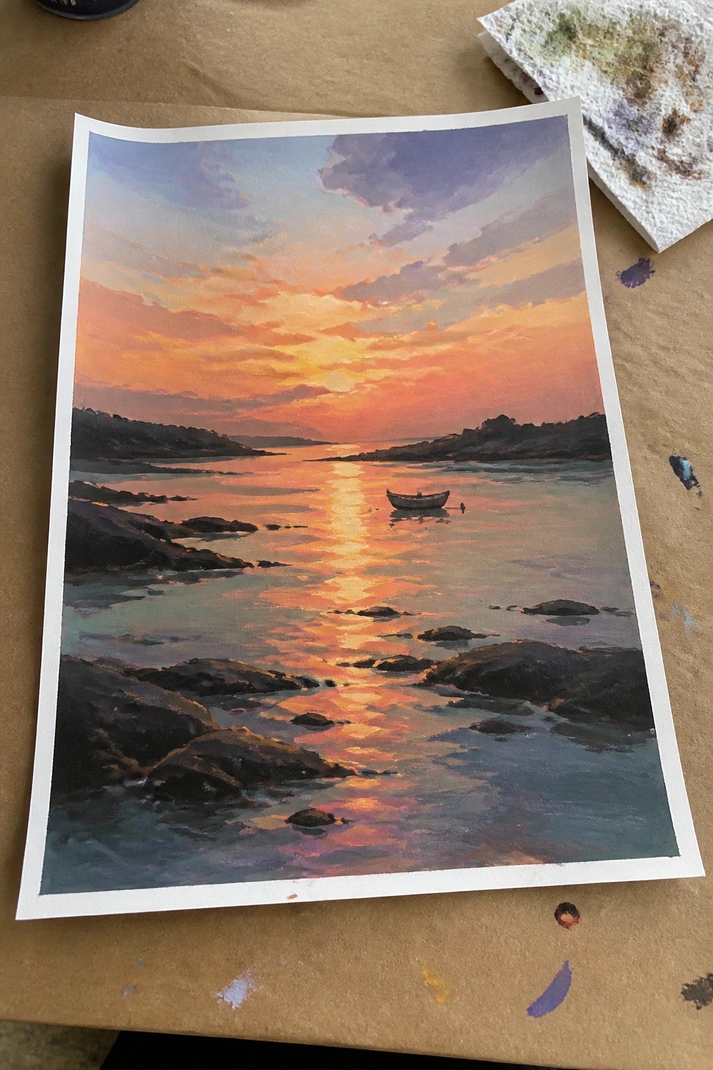 Vibrant sunset painting with orange sky, boat on reflective water and rocky shores
