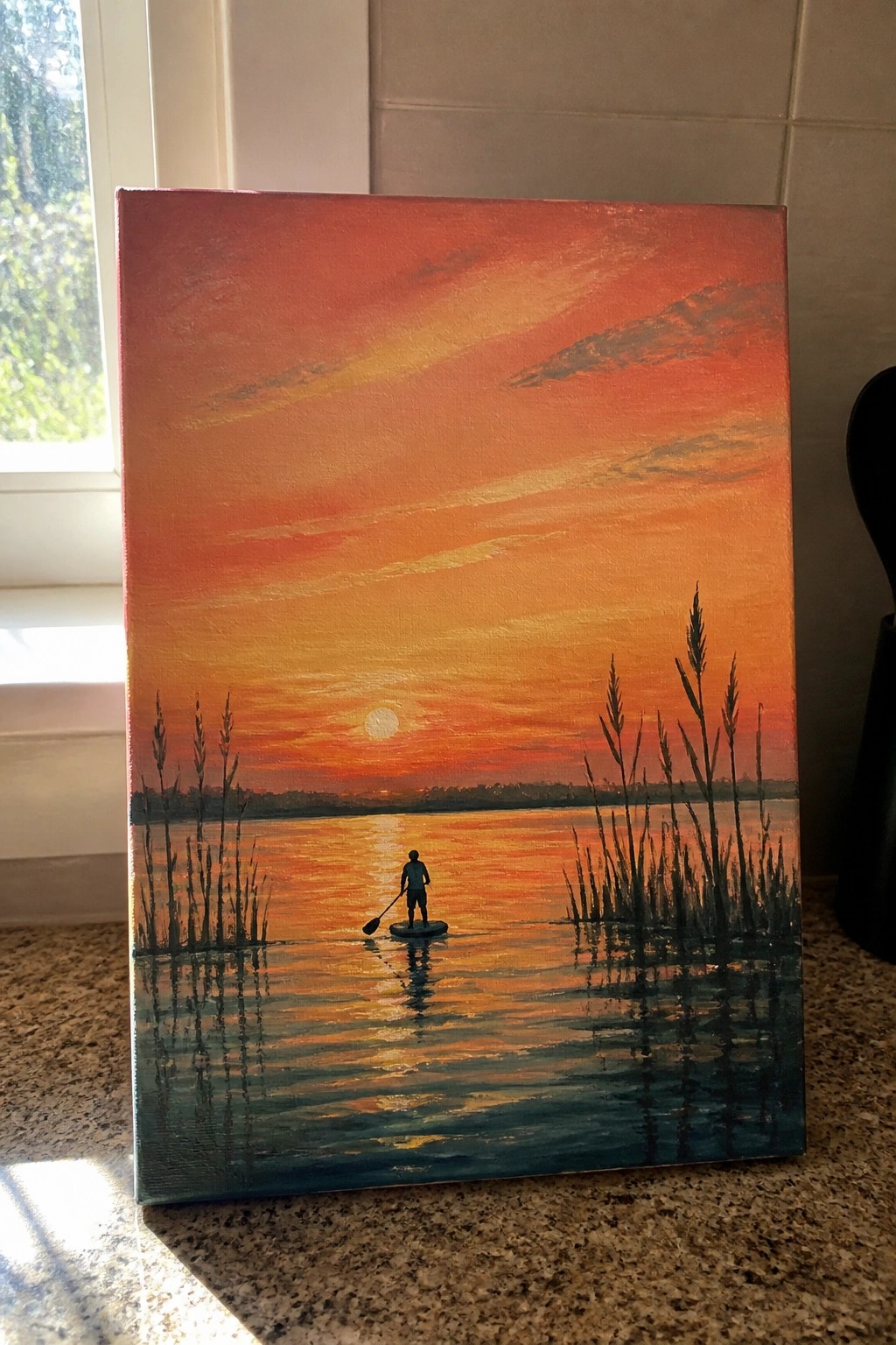 Orange sunset painting of paddleboarder on reflective water flanked by tall reeds.