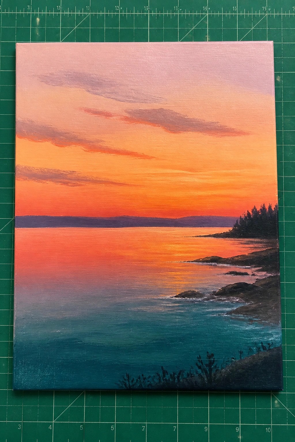 Vibrant sunset painting with orange-pink sky over reflective teal ocean and rocky shore