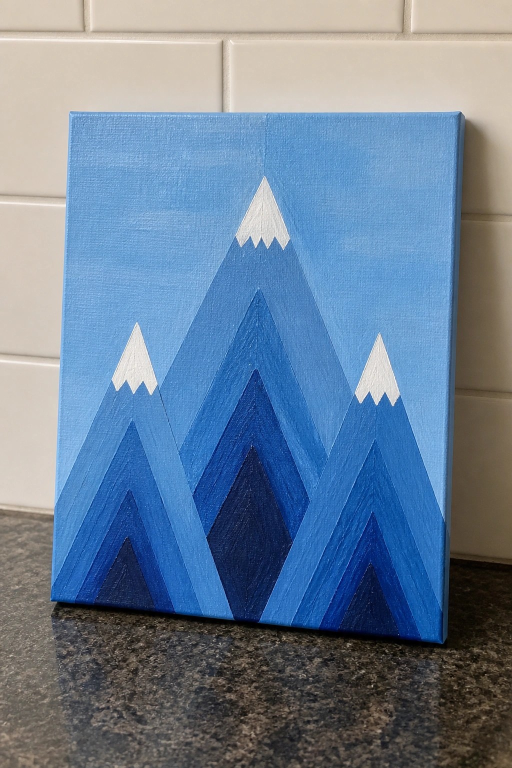 Layered blue mountain landscape painting with white peaks on canvas