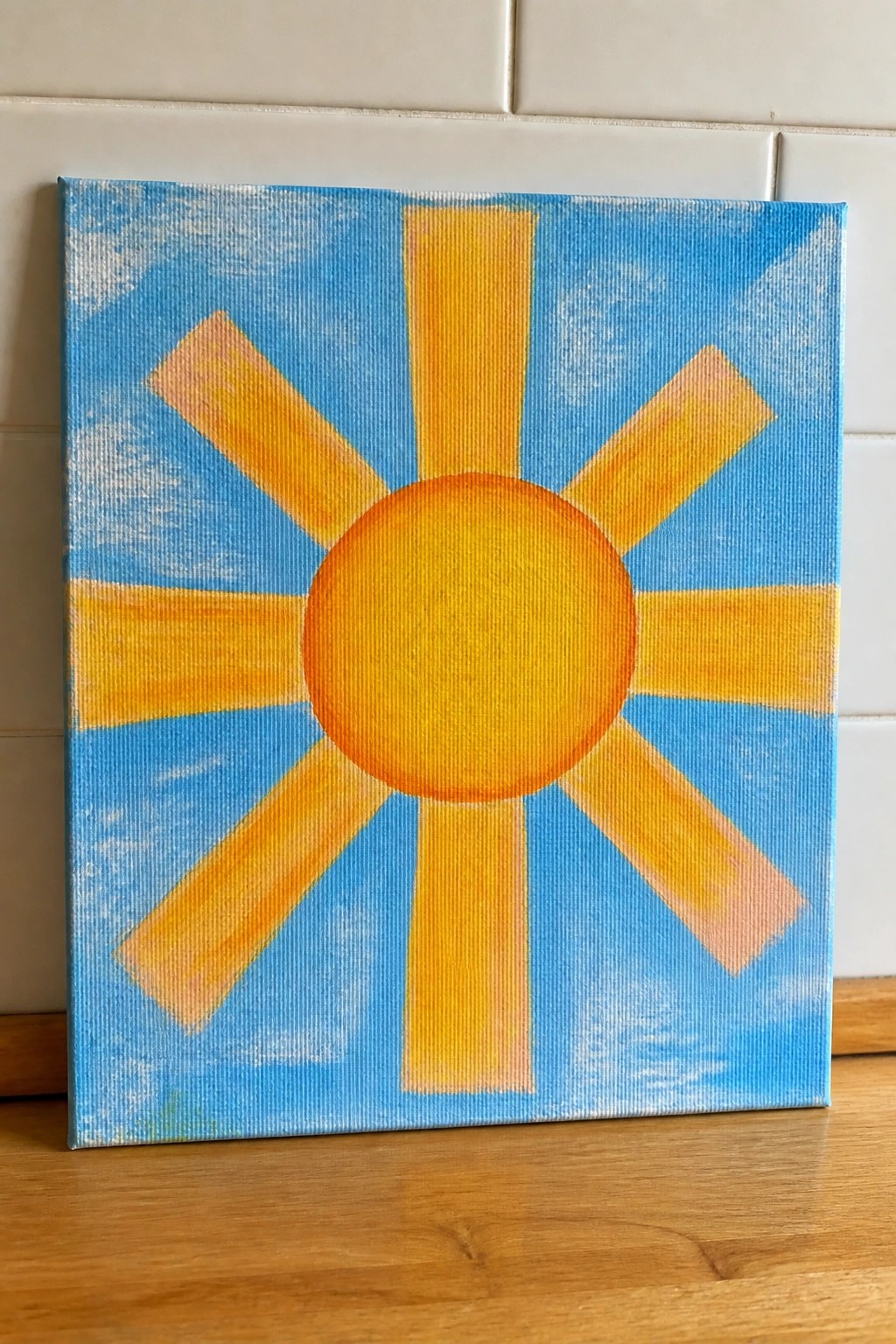 Vibrant canvas painting of yellow sun with orange rays on blue sky background