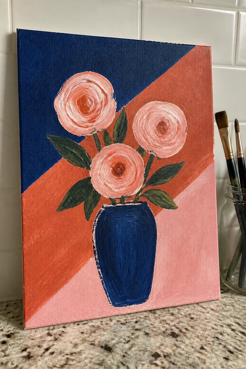 Three pink roses in blue vase on geometric navy, coral and pink canvas