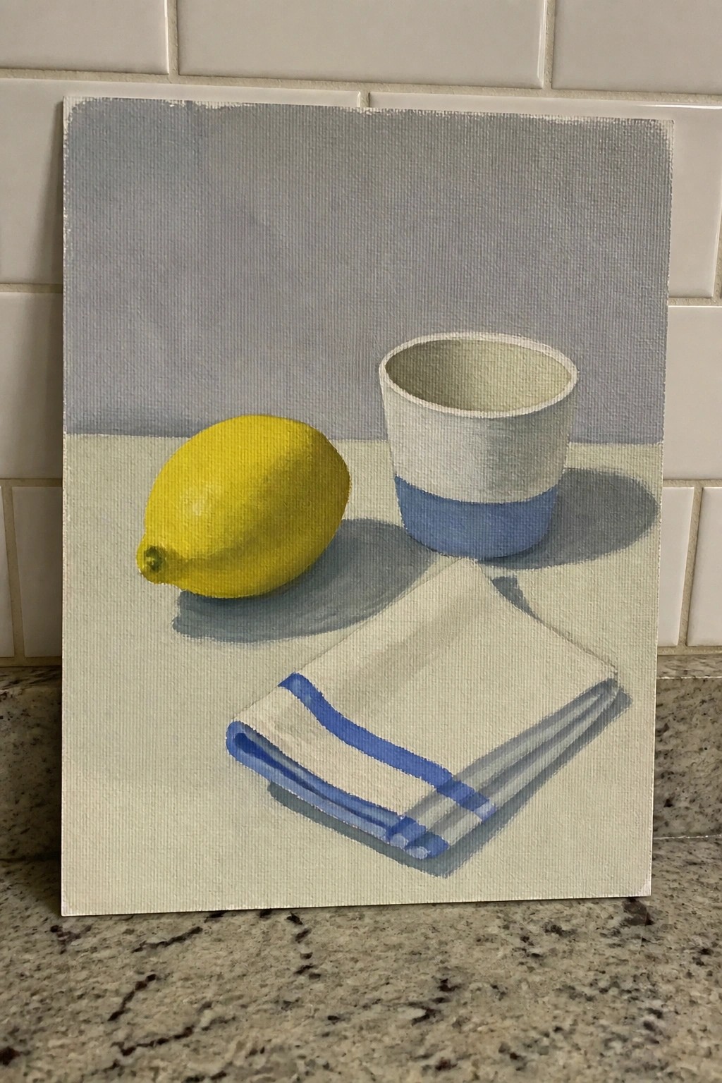 Still life painting of yellow lemon, blue-banded cup, and striped napkin on table.
