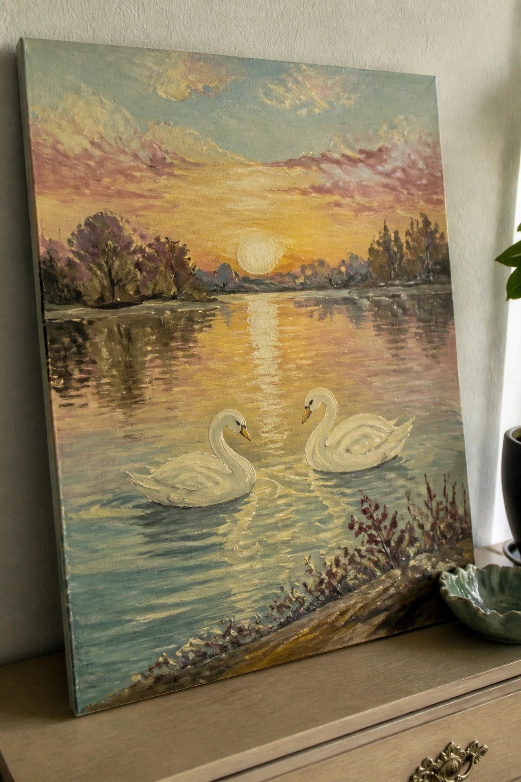 Two white swans on a reflective lake beneath a vibrant pink-orange sunset sky