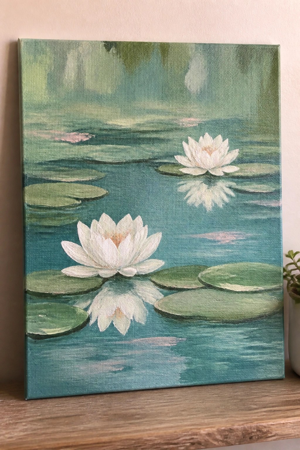 Two white water lilies with reflections float among green pads on blue-green water.