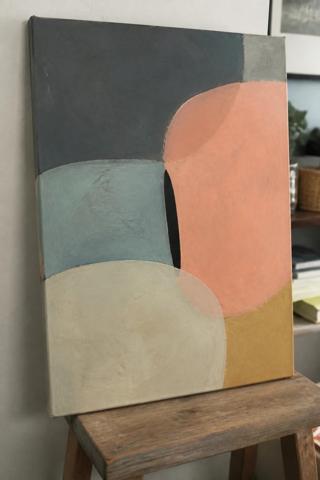 Abstract painting with curved shapes in gray, teal, beige, coral and mustard yellow on wooden stool