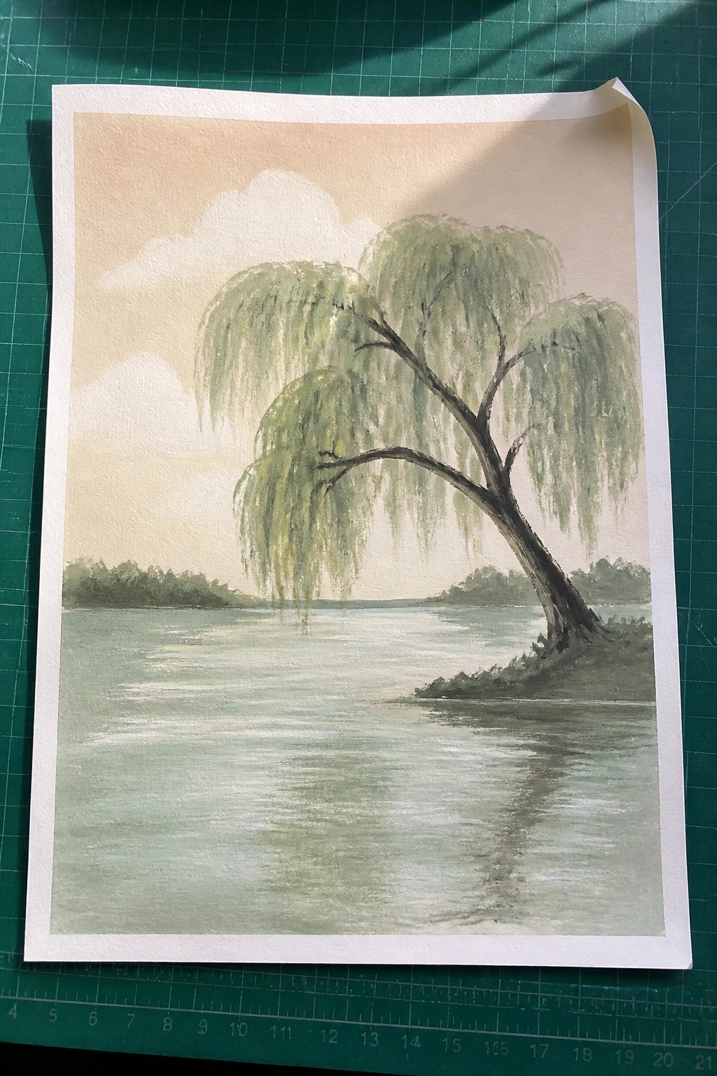 Watercolor painting of weeping willow tree by calm reflective lake under pale sky