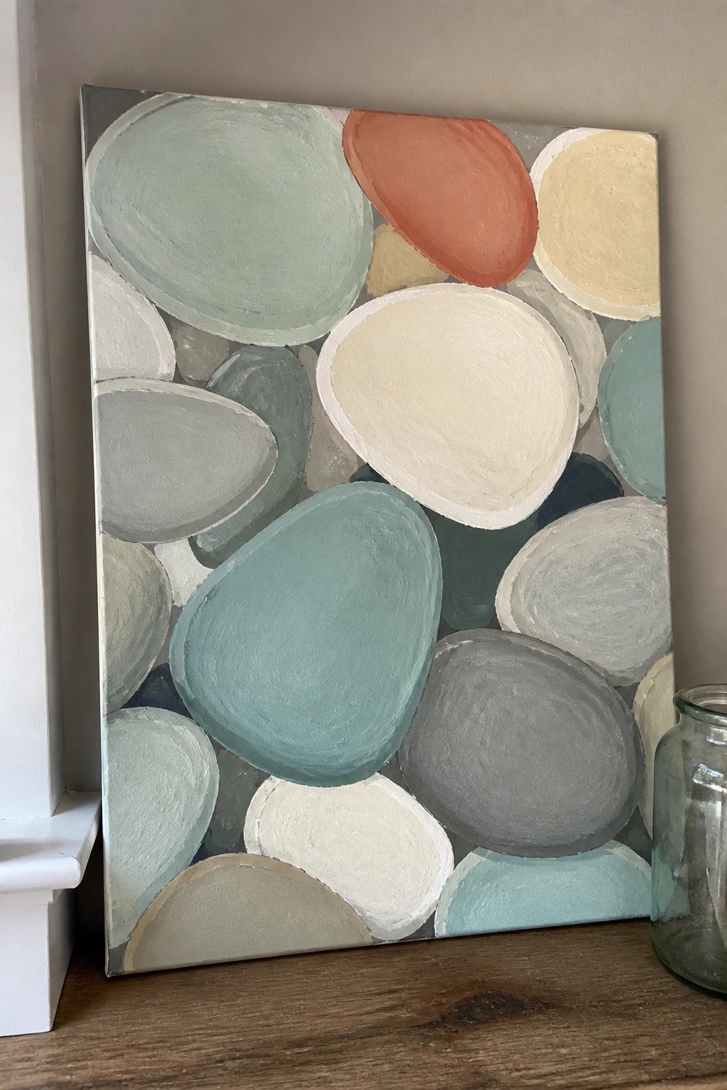 Abstract painting of overlapping ovals in teal, gray, cream, and orange on canvas
