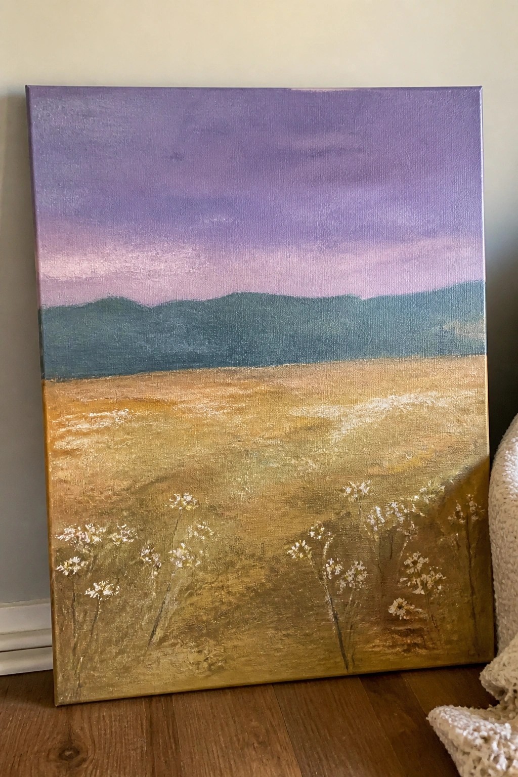 Landscape painting of purple sky over teal hills and golden field with white flowers.