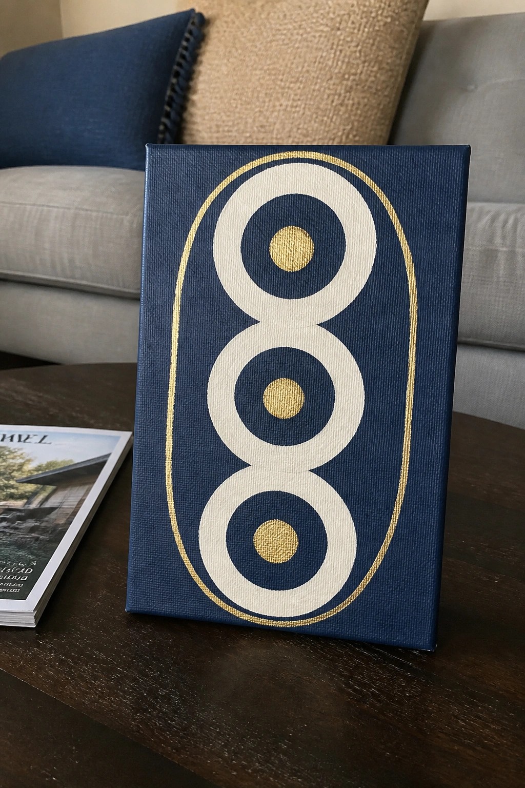 Blue canvas with gold oval border, white concentric circles, and gold centers on wood table