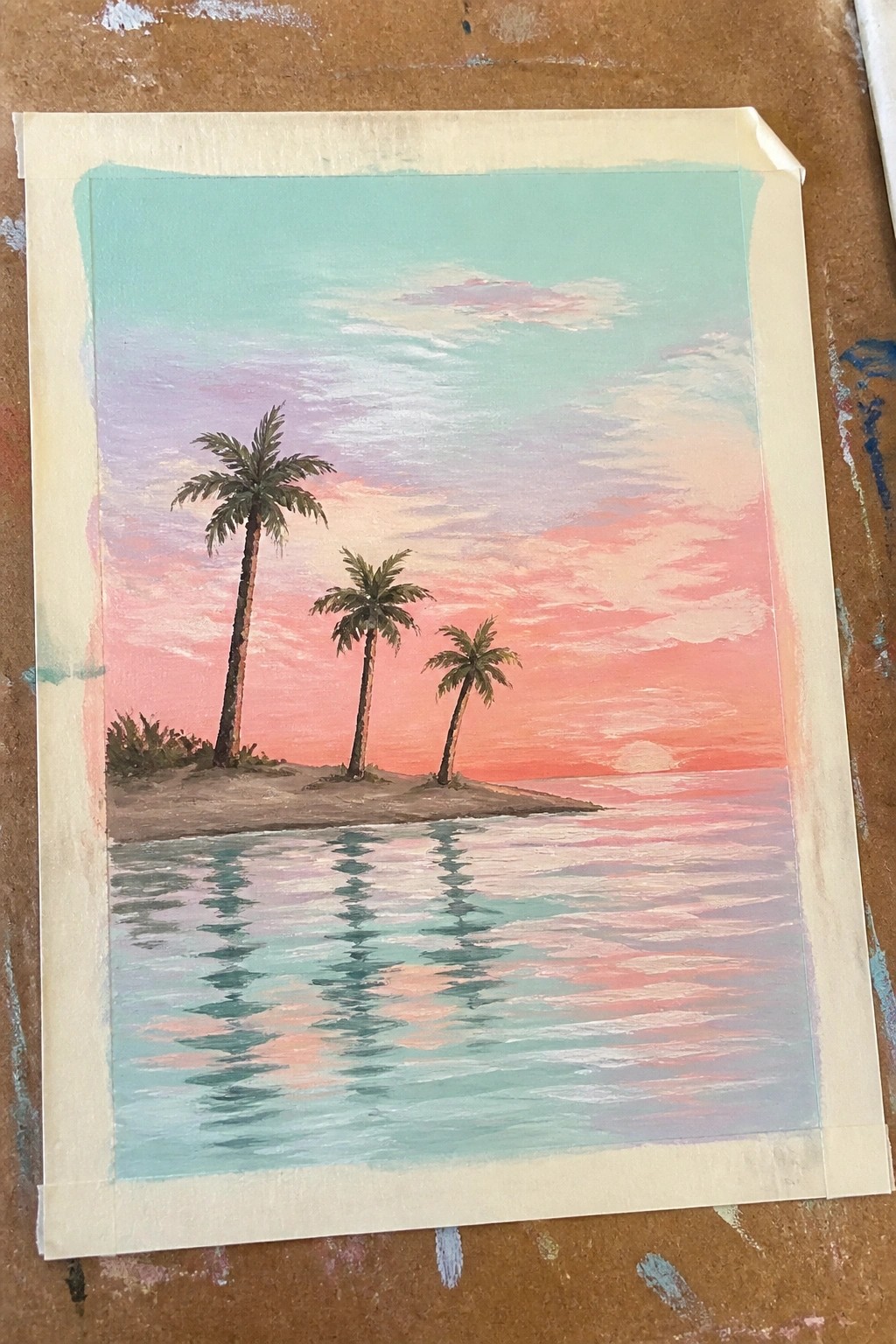 Three palm trees on sandy island reflecting in calm water under pink sunset sky.