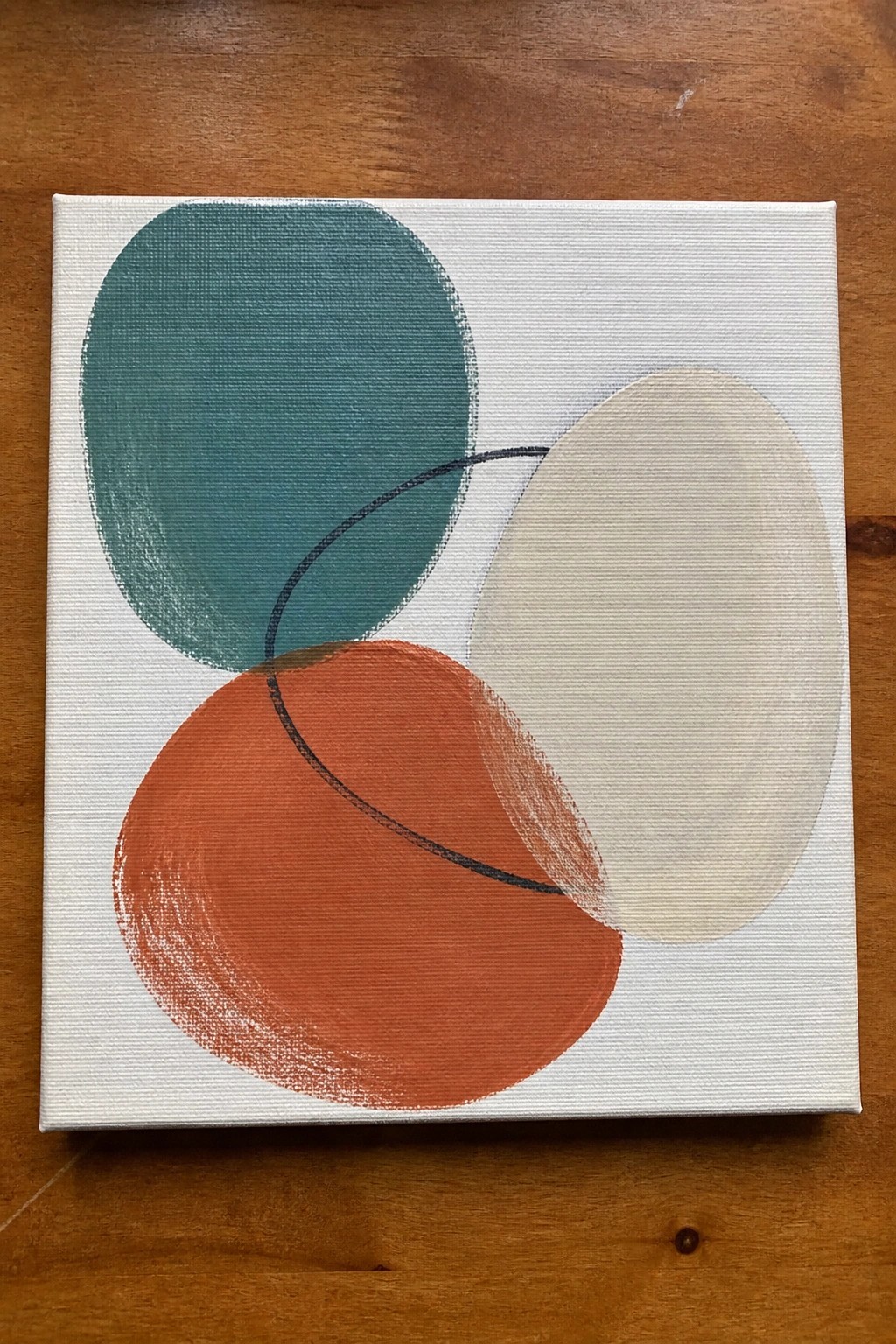 Abstract canvas painting with overlapping teal, orange, and beige circles plus black curve