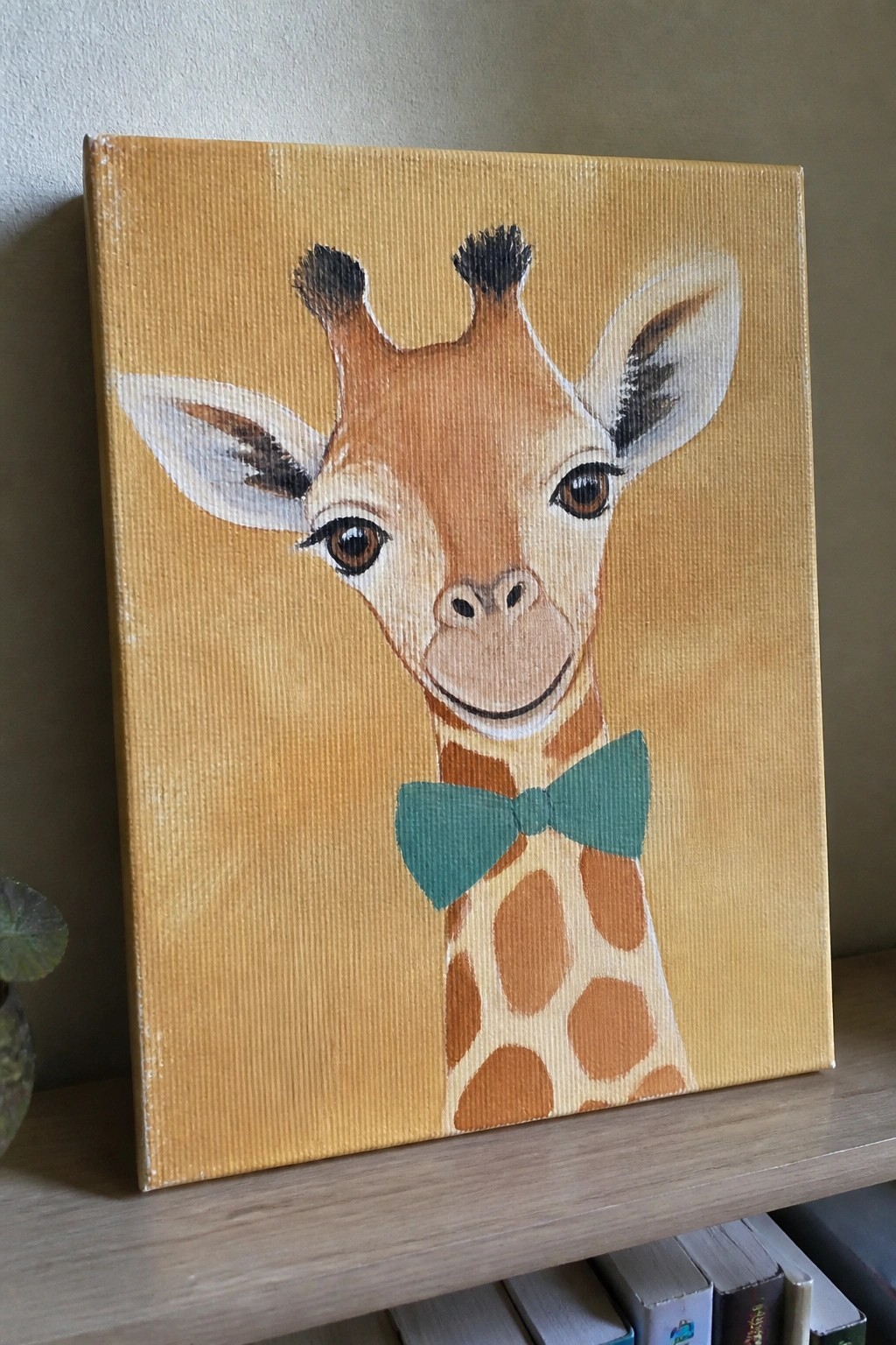 Canvas painting of smiling giraffe with teal bow tie on yellow background