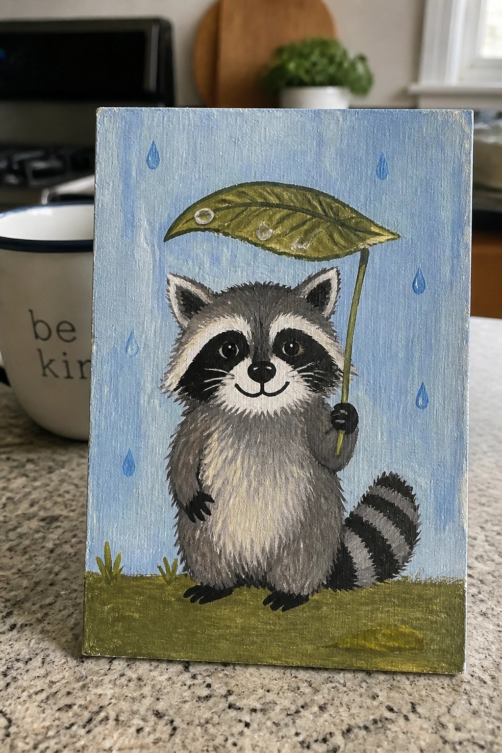 Cute hand-painted raccoon holding leaf umbrella in rain on grassy field