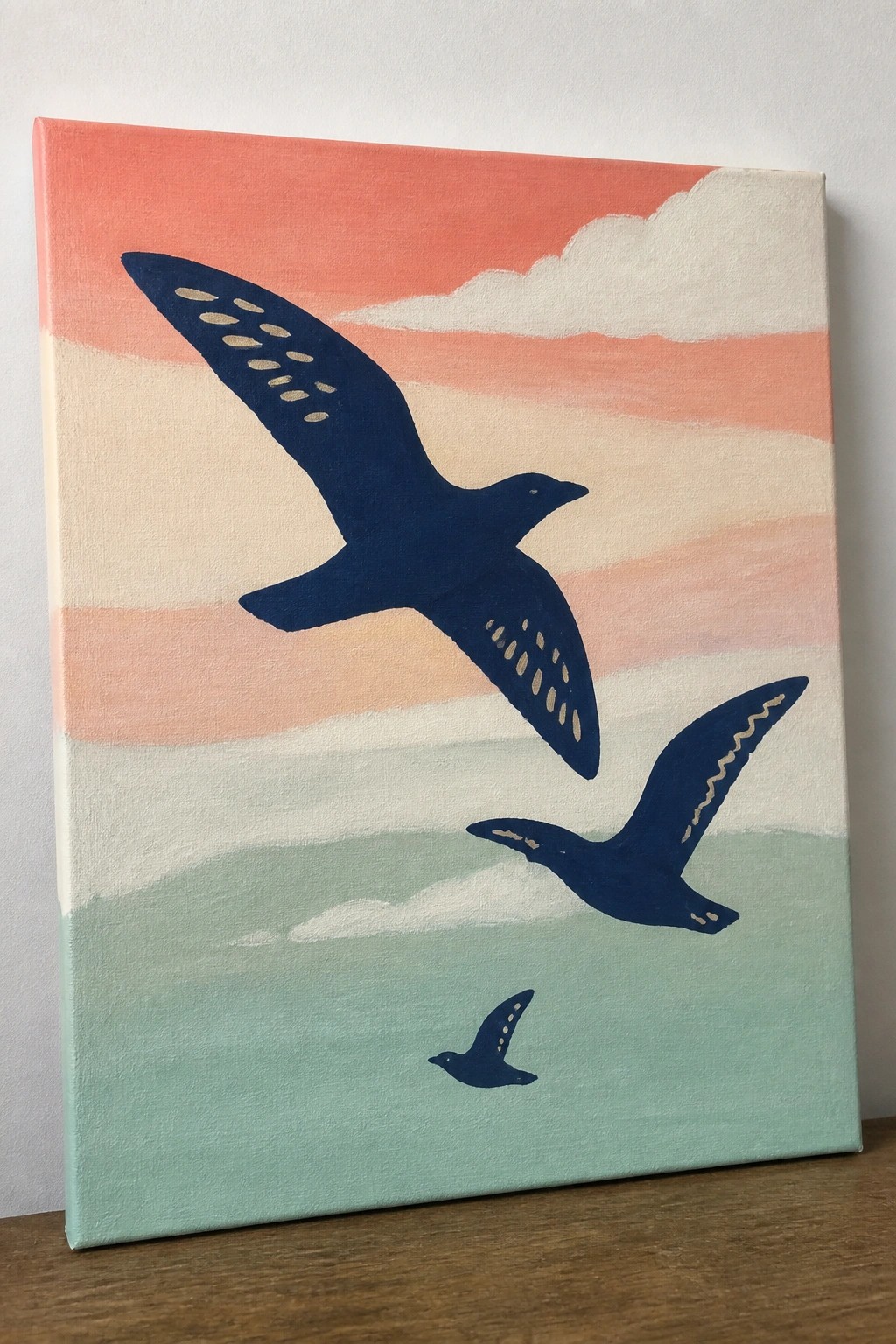 Three dark blue birds soaring across a pastel striped sunset sky painting.