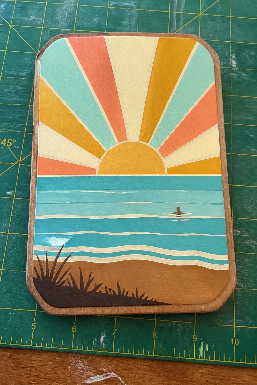 Retro wooden plaque with colorful sun rays over ocean, swimmer, and beach grass