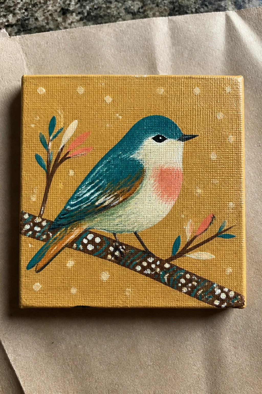 Teal-headed bird with pink cheek on dotted branch against yellow polka-dot background.