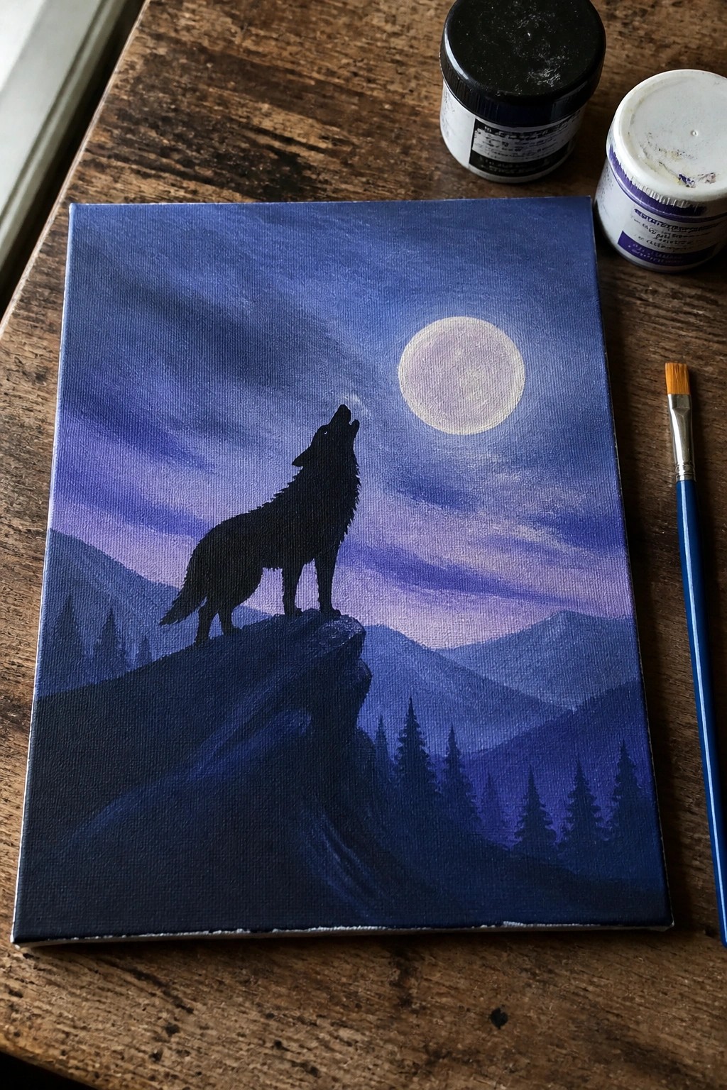 Silhouetted wolf howling on cliff under full moon in purple night sky with paint supplies.