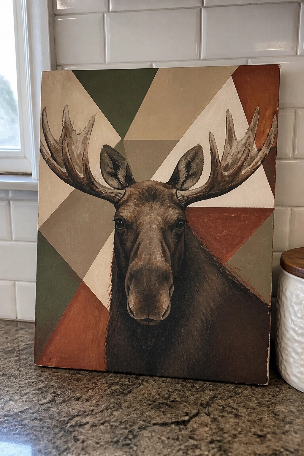 Moose head with large antlers painted on canvas with geometric earth-tone triangles
