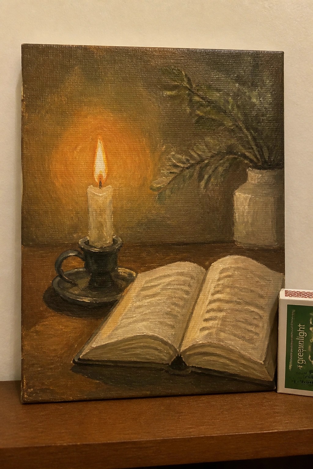 Oil painting of open book, lit candle in holder, and leafy vase on table